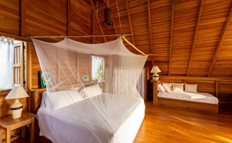 Wooden villa bedroom with soft linens at Calamocha Lodge, Manzanillo, Costa Rica