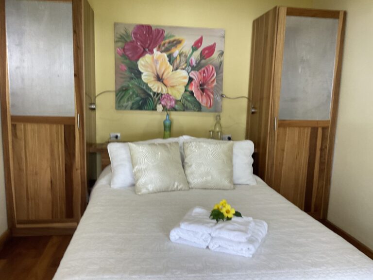 Guest room with a queen bed, fresh towels and hand-painted botanical art, Costa Rica retreat