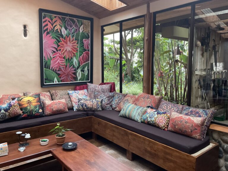 Reading lounge with a deep corner sofa, botanical art and rainforest views, Costa Rica retreat