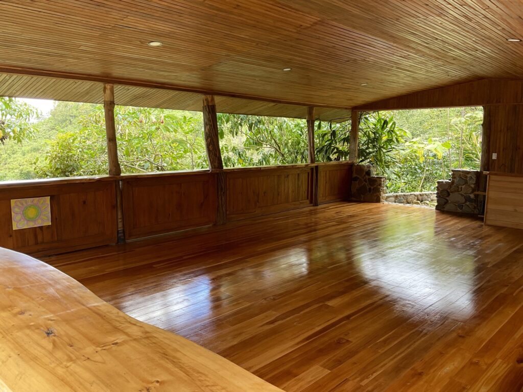 Open-air teak yoga shala at Dharma Vida with polished wooden floor and jungle views, Costa Rica