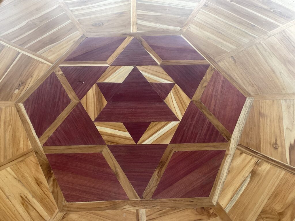 Hand-inlaid wooden mandala ceiling inside the meditation temple at Dharma Vida, Costa Rica