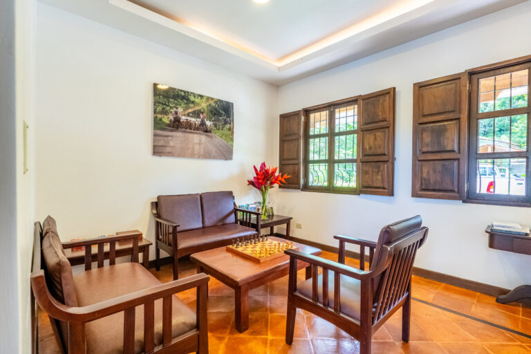 Indoor lounge with wooden armchairs and shuttered windows, Hacienda Las Vainillas Costa Rica