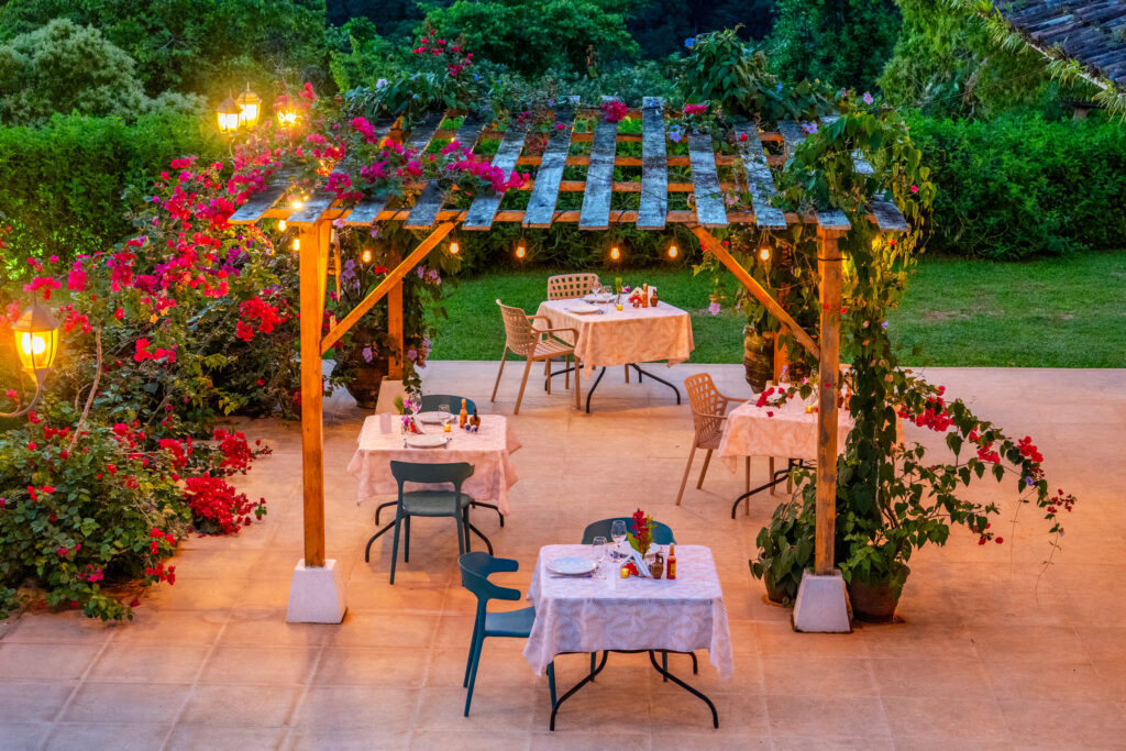 Pergola set for dinner under bougainvillea and string lights at dusk, Costa Rica
