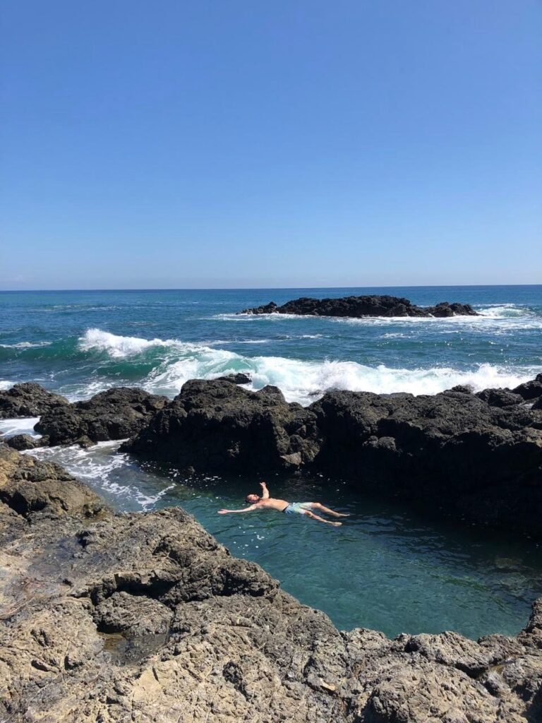 Floating in a natural tide pool among volcanic rocks on the Pacific coast, Manzanillo, Costa Rica